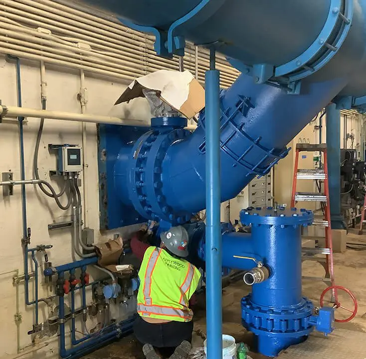 A worker is working on the pipes of an industrial plant.